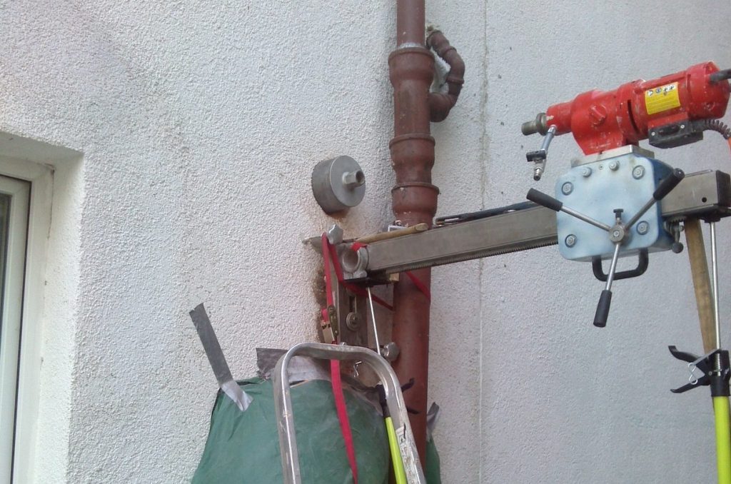 Kernbohrgerät an einer Hausaußenwand neben einem Fallrohr